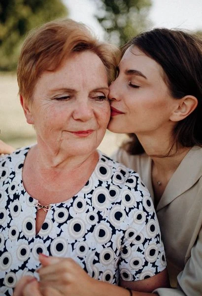 A daughter kissing her mother on the cheek outdoors